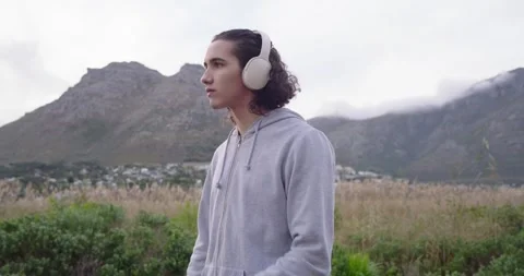Man checking smartwatch fixing headphones and jogging through field toward Stock Footage 341027123