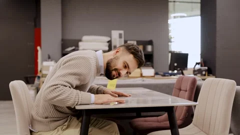 Man checking table quality in furniture store, carefully inspecting surface Stock Footage 334654105