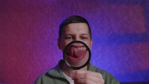 Man checking teeth with magnifying glass as a mirror Stock Footage 333757019