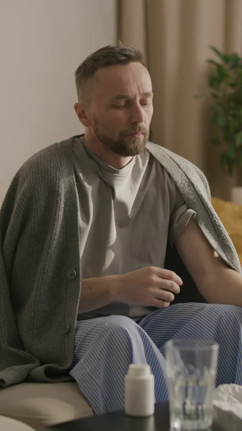 Man Checking Thermometer and Coughing while Feeling Unwell at Home Stock Footage 328356887