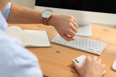 Man checking time at desk in office, closeup. Being late Stock Photos