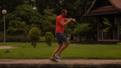 Man checking time on watch during jogging in city park, slow motion Stock Footage 141671865