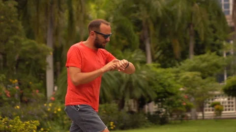 Man checking time on watch during jogging in city park, slow motion Stock Footage 141672241