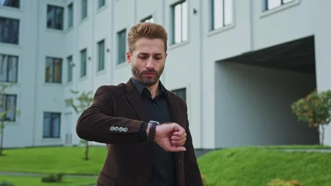 Man checking time while waiting outside a modern office in the afternoon Video stock 303798590
