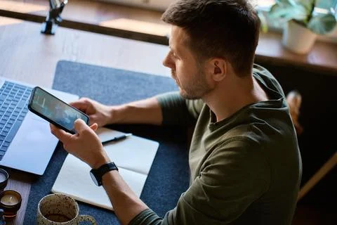 Man checking unknown caller on smartphone at desk Stock Photos