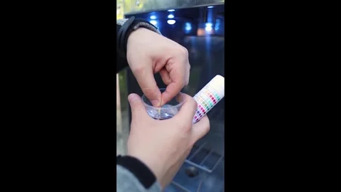 Man checking water quality at a public vending machine using a test strip. Analy Stock Footage 339879089