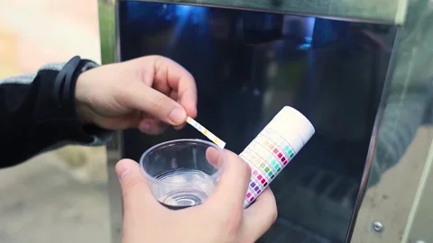 Man checking water quality at a public vending machine using a test strip. Analy Stock Footage 339879194
