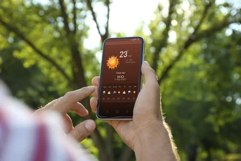 Man checking weather using app on smartphone outdoors, closeup. Data, sun a.. Stock Photos