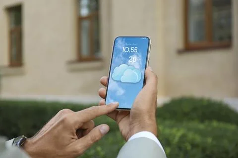 Man checking weather using app on smartphone outdoors, closeup. Data and il.. Stock Photos