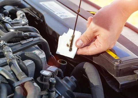 A man checks the engine oil level on the dipstick with a rag. Maintaining an 写真素材