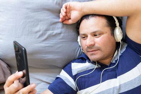 Man checks his phone while lying in bed, aerial view Stock Photos