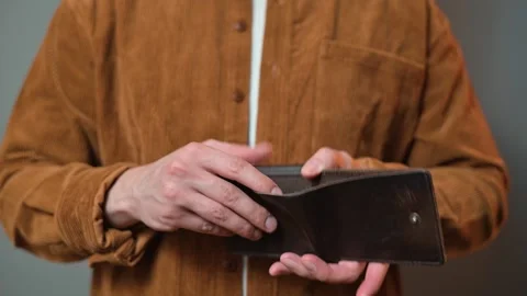 A man checks his wallet and shows the camera that it's empty. Poverty, bankrupt Stockbeeldmateriaal 337643229