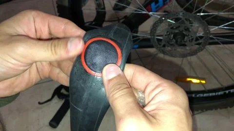 A man checks how he pasted a patch on the tire of a Bicycle wheel Stock Footage 142697970