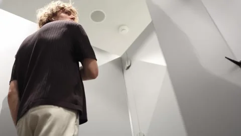 Man checks how his T shirt fits from the back before deciding to buy it Stock Footage 344856141