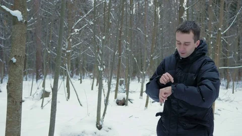 A man checks the messages on the smart watch in the winter snowy forest. He Stock Footage 71209033
