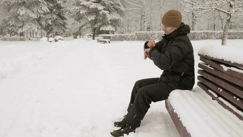 A man checks the messages on the smart watch in the winter snowy park. He Stock Footage 71221145