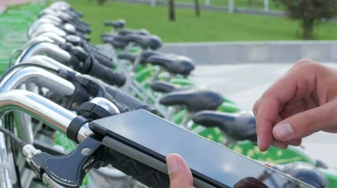 A man checks the messages on the Tablet PC on a bike parking lot. He's going to Stock Footage 67612169