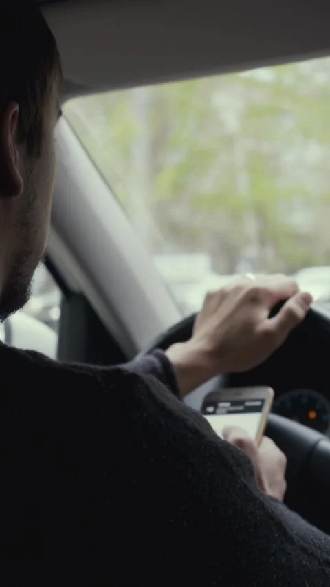 Man checks a navigation app on his phone while driving, one hand on the wheel Stock Footage 346859491