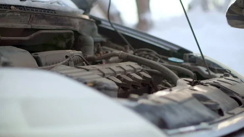 A man checks the oil level in the engine of his car. It is very cold Видео 102155396