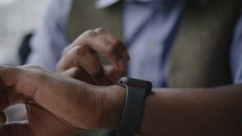 Man checks smartwatch while enjoying coffee at a busy cafe in the afternoon Stock Footage 312578426