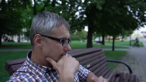 Man checks time sitting on bench and enjoying weather Stock Footage 168512481
