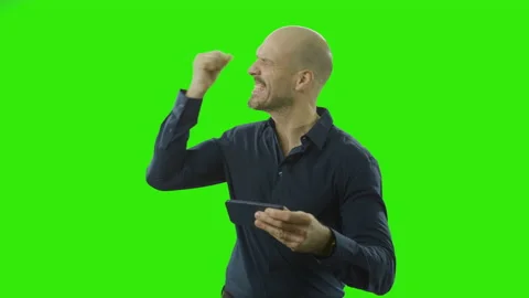 Man cheering and pointing at his phone in front of a green screen Stock Footage 166512819