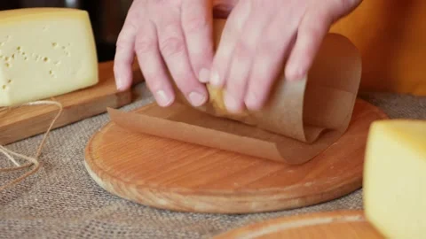 Man cheesemaker wraps cheese in craft paper, packs for sale, buyer. Gift Stock Footage 164668709