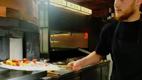 Man chef carefully places prepared pizza into oven Stock Footage 326370342