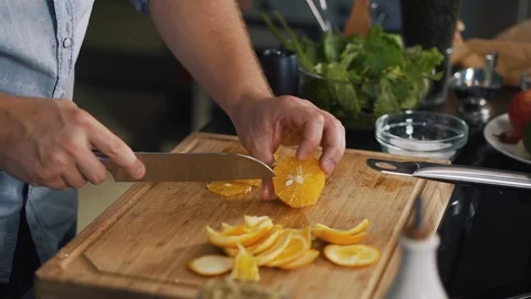 Man chef cut orange into thin slices, clean bones with knife, fruit, close-up Stock Footage 125729470