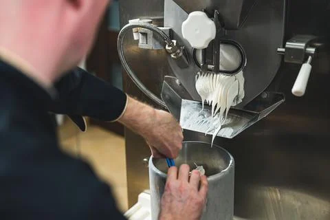 Man chef getting white ice cream from the ice cream maker machine in the small Stock Photos