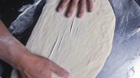 Man chef hands stretching pizza dough to a circle top view zooming out Stock Footage 143647602