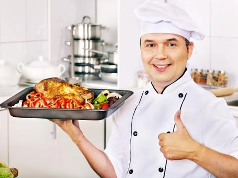 Man in chef hat cooking chicken Stock-Fotos