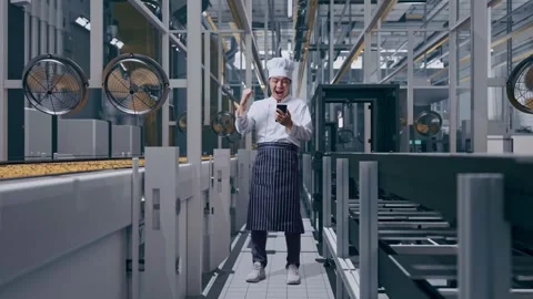 Man Chef Looking At Smartphone Then Screaming Goal Celebrating In Cookie Factory Vidéo 318082423