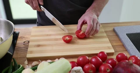 Man chef slices cherry tomatoes in halves cutting board Stock Footage 287280533