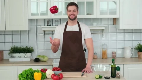 A man chef throws a vegetable and catches it with his hand while standing in the Stock Footage 151389170