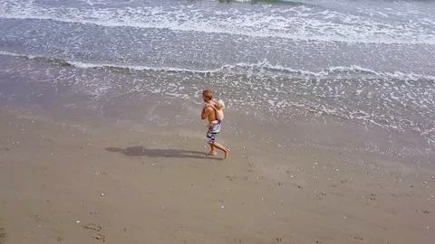 Man with child on his back runs on sea beach, training or fitness, aerial view Video stock 109900601