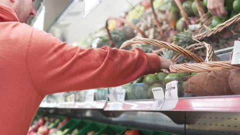 A man chooses an avocado in a supermarket Stock Footage 235657181