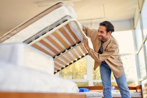 A man chooses a bed in a store, examines a frame with slats. Purchase of a ma Stock Photos