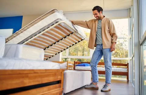 A man chooses a bed in a store, examines a frame with slats. Purchase of a ma Stock Photos