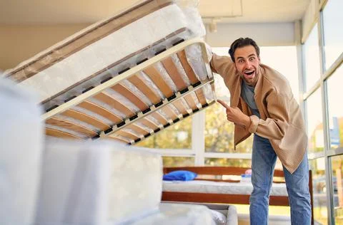A man chooses a bed in a store, examines a frame with slats. Purchase of a ma Stock Photos