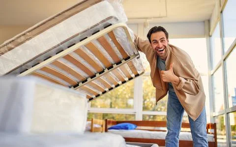 A man chooses a bed in a store, examines a frame with slats. Purchase of a ma Stock Photos