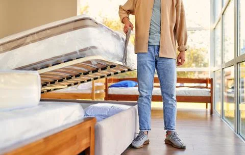 A man chooses a bed in a store, examines a frame with slats. Purchase of a ma Stock Photos