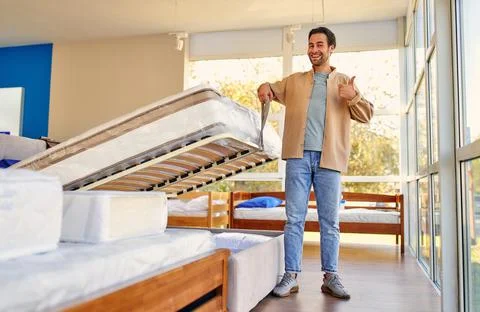 A man chooses a bed in a store, examines a frame with slats. Purchase of a ma Stock Photos