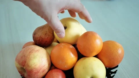 Man chooses between an apple and a tangerine. Stock Footage 150079514