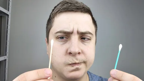 Man chooses between a plastic and a wooden ear stick. The concept of protecting  Stock Footage 126407069