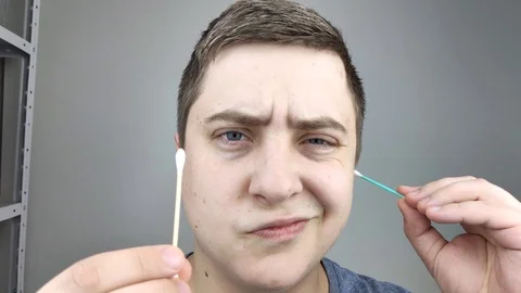 Man chooses between a plastic and a wooden ear stick. The concept of protecting  Stock Footage 126407097