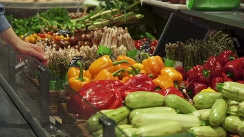 Man chooses between red and yellow bell peppers Stock Footage 76680993