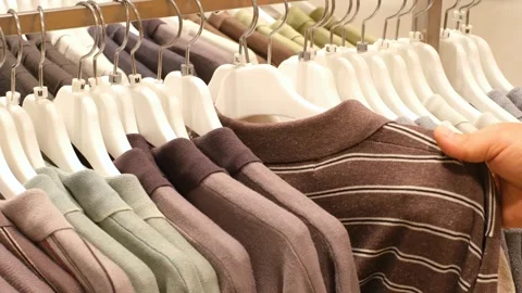 Man chooses clothes hanging on hanger in store. 库存影片 340182502