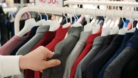 A man chooses clothes hanging on hangers in retail mall, close up. Stock Footage 167955344
