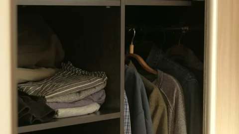 Man chooses clothes in the wardrobe in the sunlight Stock Footage 168729271